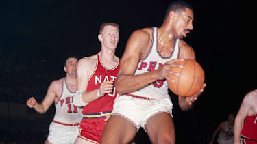 1962 - Philadelphia, PA: Close up of Wilt Chamberlain (#13), as he comes down with rebound and looks for teammate. Behind him are John Kerr (#10) of the Syracuse Nationals and Paul Arizin of the Philadelphia Warriors. Color slide.