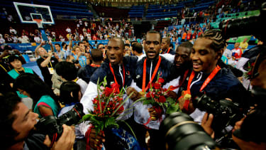 FILE - Kobe Bryant, from left, LeBron James, Dwyane Wade and Carmelo Anthony, of the U.S. Olympic basketball team, are surrounded by photographers as they celebrate after beating Spain 118-107 in the men's gold medal basketball game at the Beijing 2008 Olympics in Beijing. A documentary on the 2008 U.S. men’s basketball team known as the “Redeem Team,” with executive producers including Lebron James and Dwayne Wade, will premiere on Netflix in October. (AP Photo/Dusan Vranic, File)